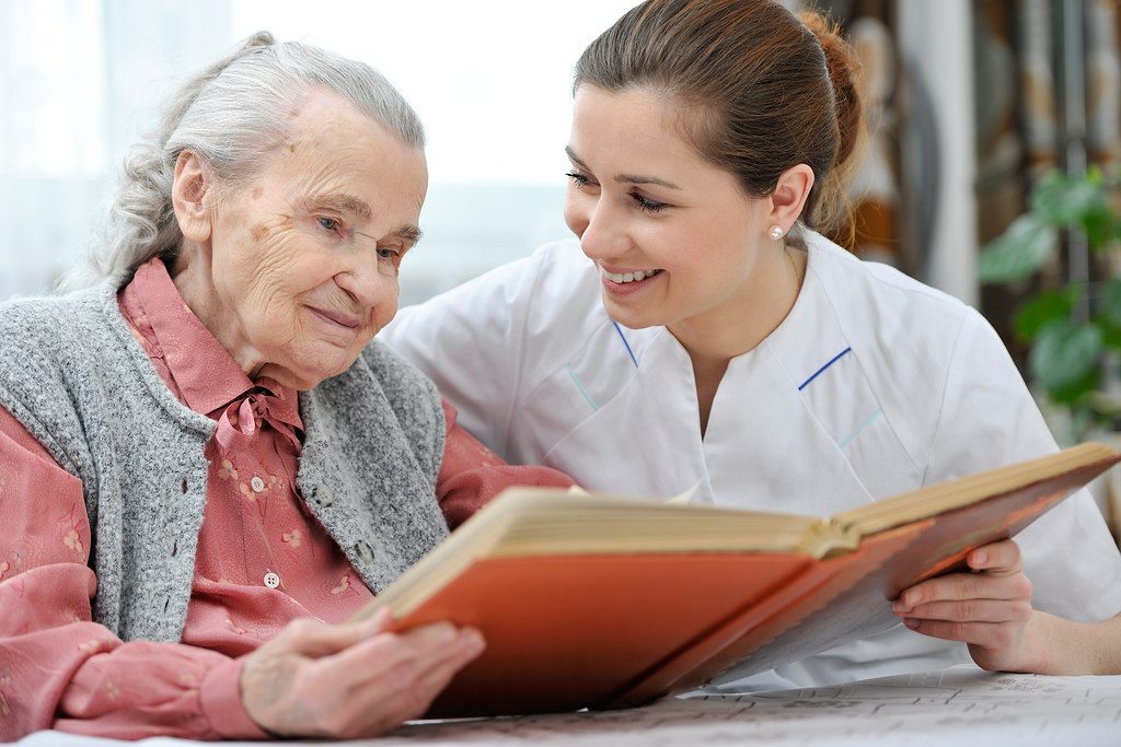 A caregiver and a resident looking through a photo album together
